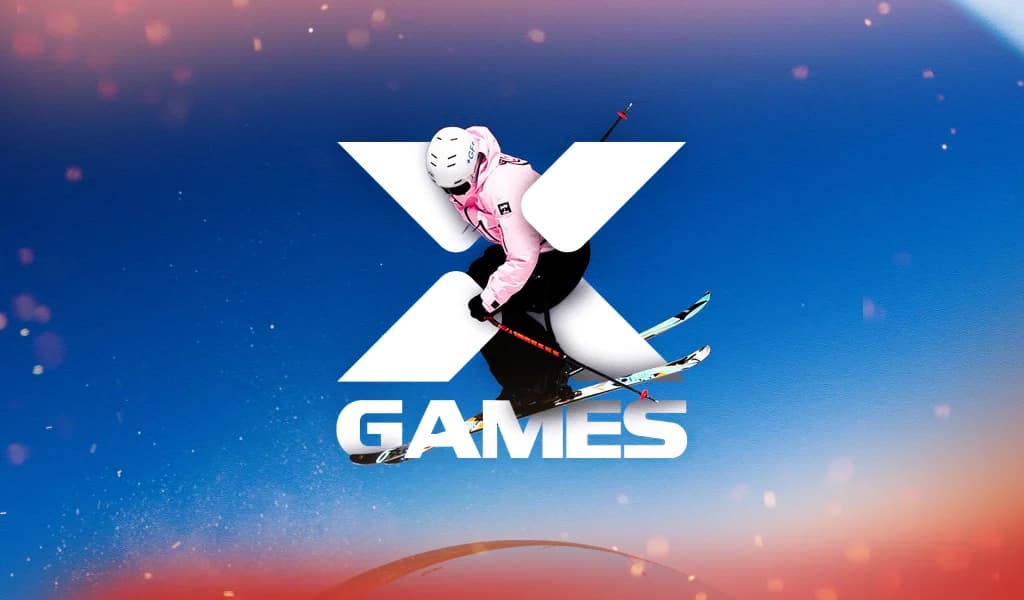 Skier midair against a blue sky with the “X Games” logo prominently displayed. 