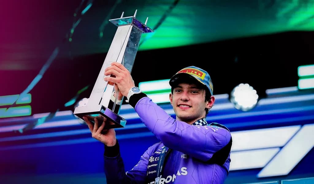 Kimi Antonelli holding the Miami Grand Prix winner's trophy on the podium in his Mercedes race suit.