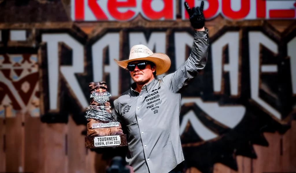 Kyle Strait holding a Red Bull Rampage Toughness trophy aloft in a cowboy hat and grey jersey in Virgin Utah 2025.
