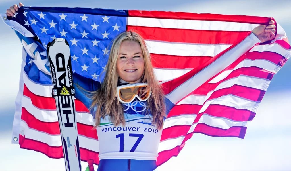 Lindsey Vonn holding an American flag after an alpine skiing event at the Winter Olympics.