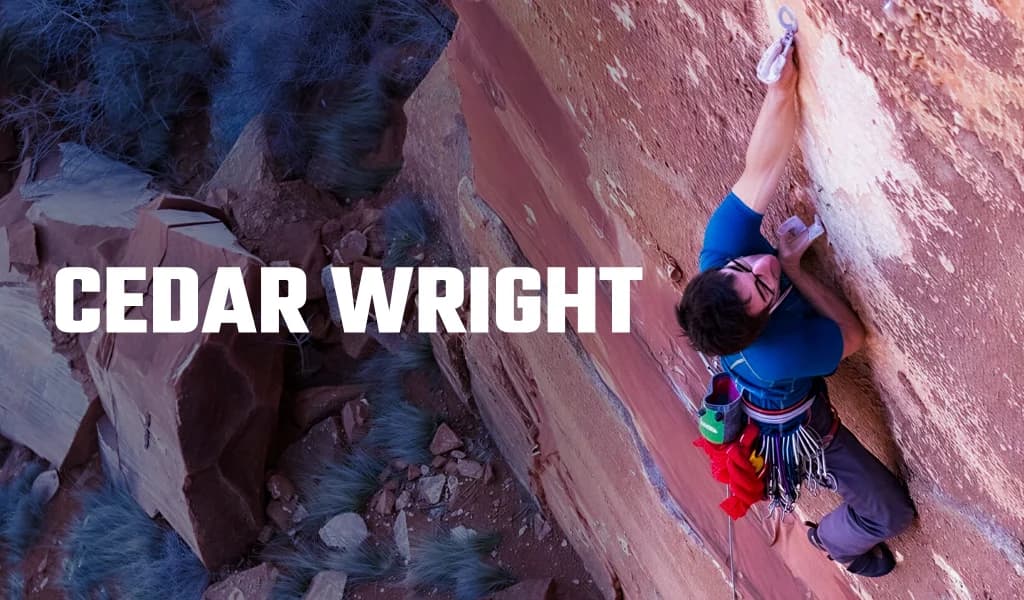 Cedar Wright climbing a red sandstone wall with a rack of gear on his harness and text Cedar Wright.