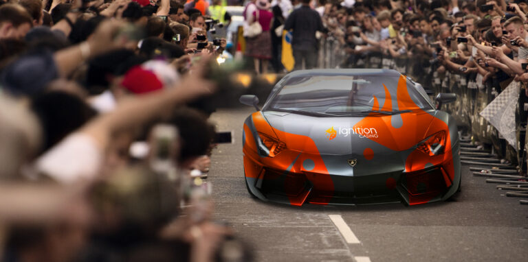 A car taking part in the Gumball 3000 rally is driving in the middle of the crowd