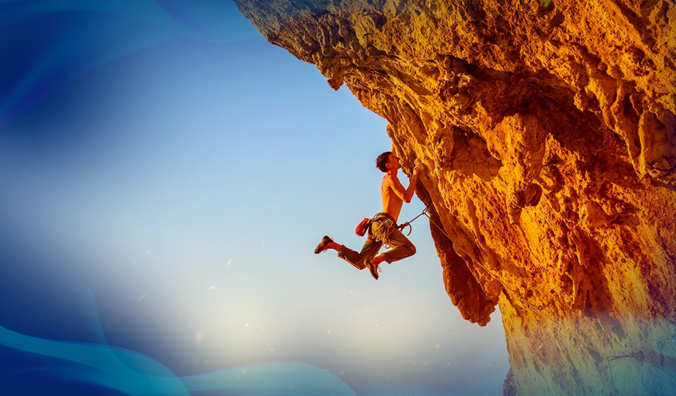 Rock climber ascending an orange cliffside, suspended mid-air with clear blue skies in the background.