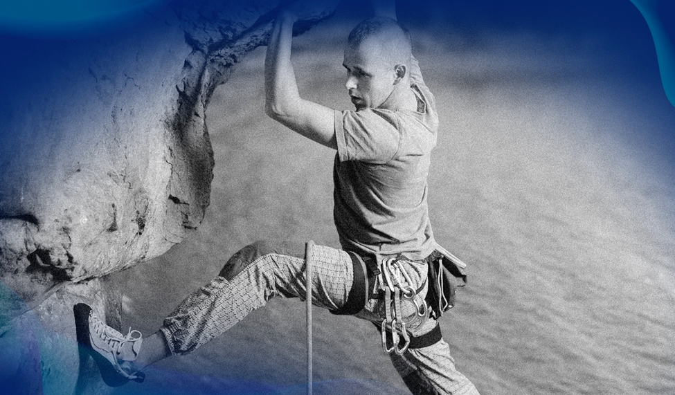 A black-and-white image of a climber gripping a rock while suspended over a body of water.